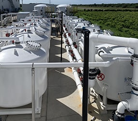 A pressure filter system in an industrial setting, consisting of filter tanks, pipes, valves, and media layers for effective water filtration.