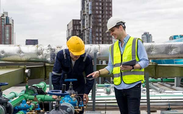 Workers inspecting pipe at facility